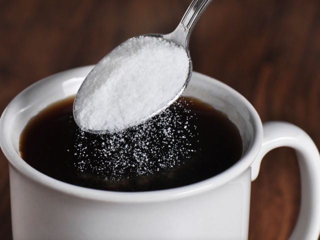 Person putting sweetner into coffee