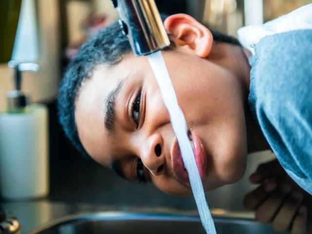 Child drinking from faucet