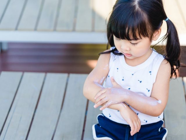 Child applying sunscreen